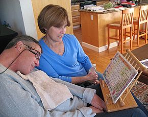 A man with ALS communicates with his wife by pointing to letters and words with a head mounted laser pointer.